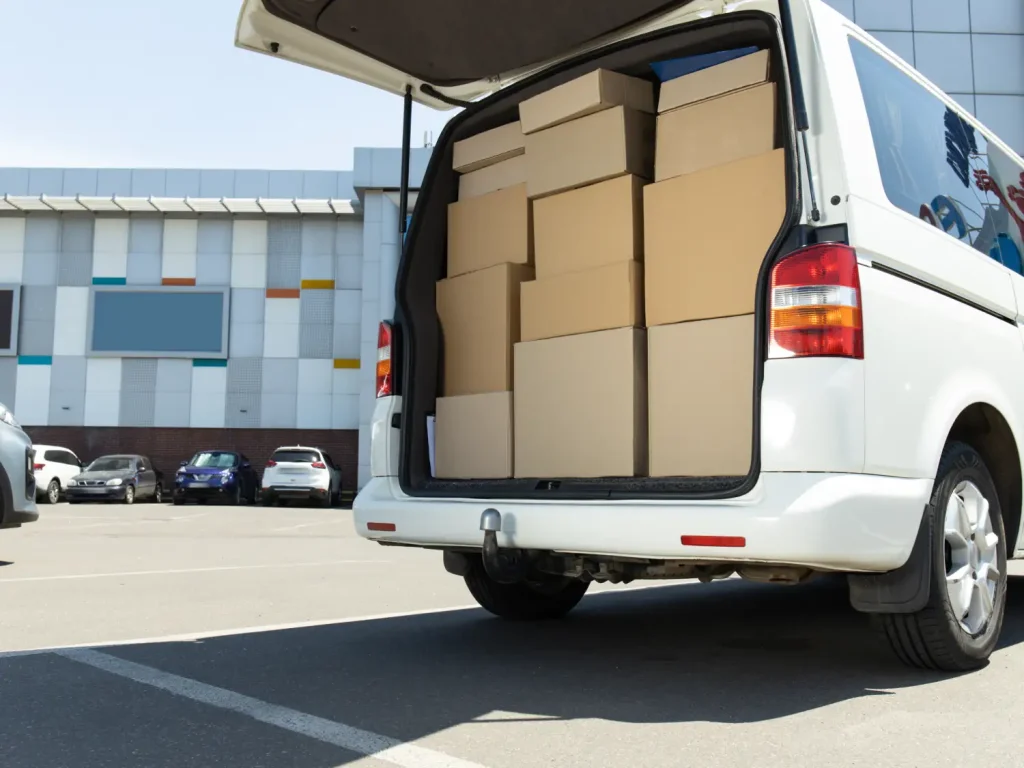 Die geöffnete Heckklappe eines weißen Transporters, der bis zum Rand lückenlos mit gestapelten Umzugskartons gefüllt ist