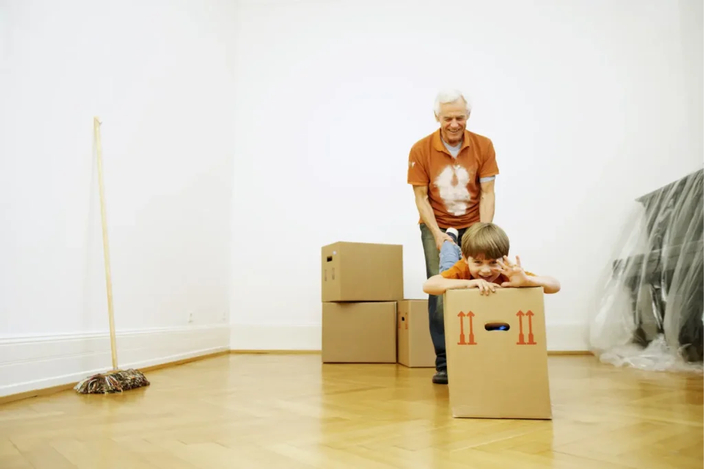 Großvater spielt mit Enkelkind im Umzugskarton für einen stressfreien und entspannten Umzugstag.